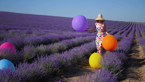 woman in a multicolored suit with circles and a hat holds large inflatable