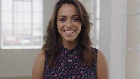 Retrato-De-Una-Atractiva-Joven-Hispana-Riendo-Alegre-Mirando-La-Cámara-Usando-Una-Hermosa-Blusa-Floral-En-El-Fondo-Del-Apartamento