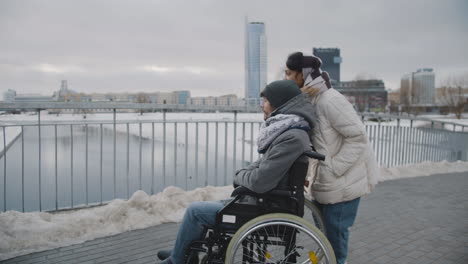 muslim woman and her disable friend looking at something in the distance in city in winter