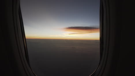 view of beautiful sunrise or sunset from a commercial plane window then push in dolly to the window to see the clouds and sky while the plane turns.