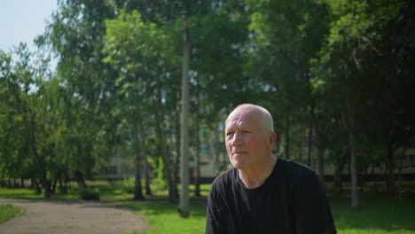 close-up of an elderly man in a black shirt catching a ball throws it back, with a focused expression