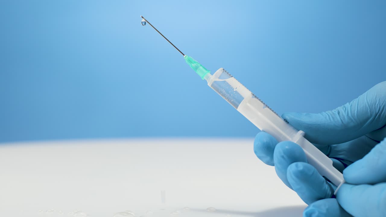 외과 조교가 주사 바늘을 준비하고 플라스틱 주사에서 공기를 아 니다.