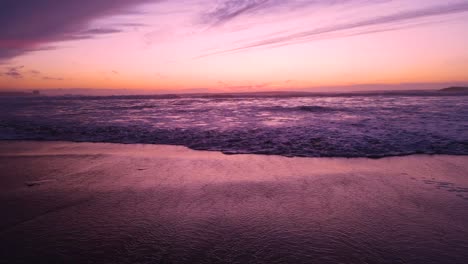 pink ocean waves roll in at sunset