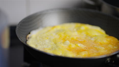 opened, squished egg sizzling in frying pan on kitchen stove during cooking prep