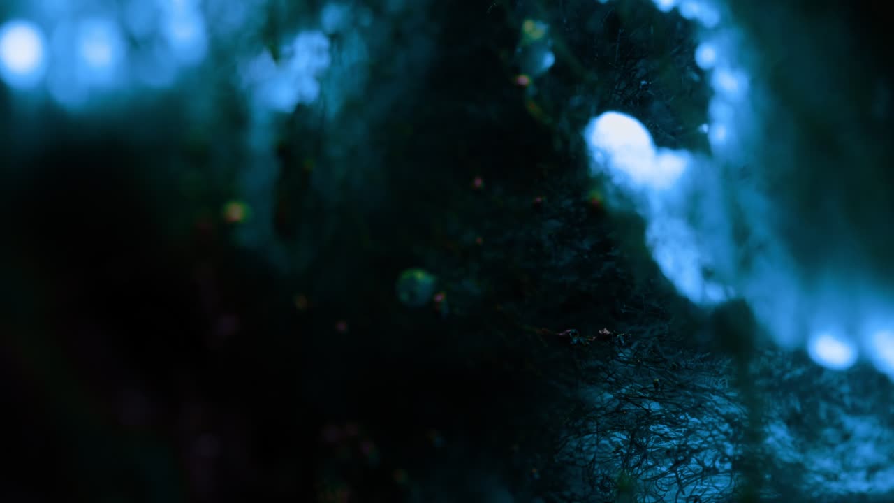 Una piccola scintilla luminosa di energia elettrica blu cade su una rete scura e suggestiva