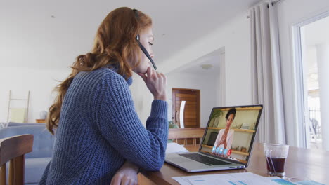 mujer caucásica con auriculares de teléfono haciendo una videollamada con una colega en una computadora portátil en casa