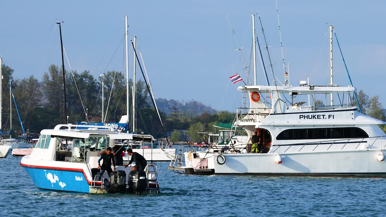 Fishing boats gently sway in Phuket's harbor under clear skies, showcasing a serene maritime scene with vibrant colors and calm waters