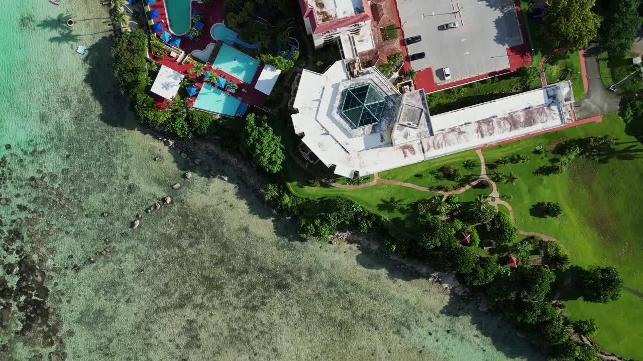 Bird's eye aerial view of scenic coastal resort with lush greenery, hotel building, and swimming pool at Hilton Guam, USA