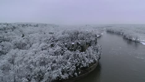 Cirle-aerial-shot-of-beautful-frozen-forest-hill,-snowy-landscape-and-river