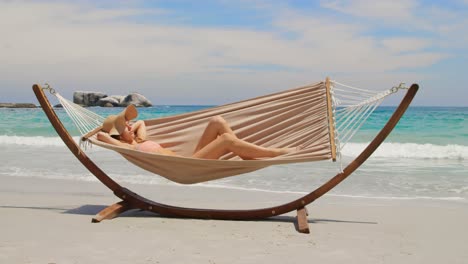 Side-view-of-Caucasian-woman-relaxing-in-a-hammock-at-beach-4k