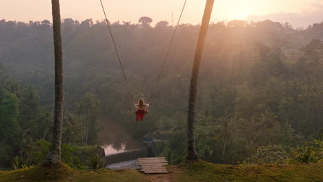 tourist woman swinging over tropical rainforest at sunrise travel girl sitting on swing with scenic view enjoying freedom on vacation having fun holiday lifestyle 4k