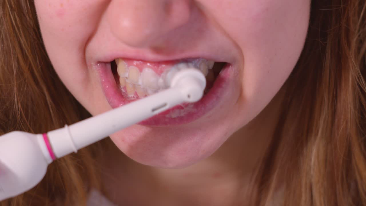A Lady is Using an Electric Toothbrush to Brush Her Teeth - Close Up