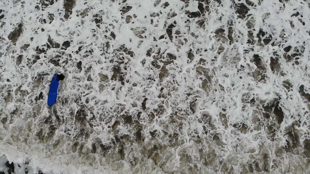 Birds eye view of Surfers paddling out to ride the waves in Scarborough, Yorkshire, UK