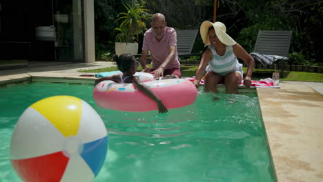 diverse grandparents enjoying pool time with granddaughter on inflatable donut float