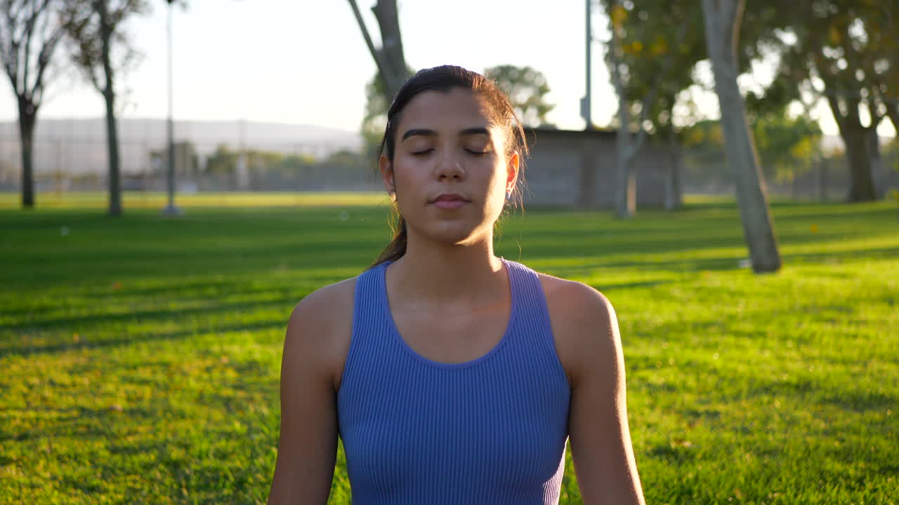 una hermosa joven yogui sentada en una estera de yoga en una meditación relajante en el parque al amanecer