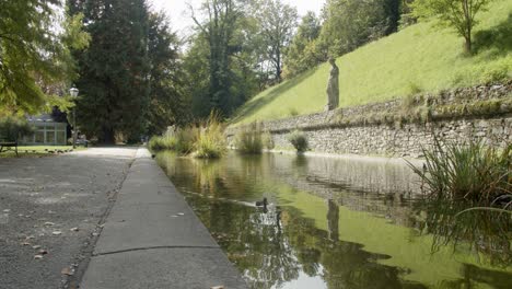 Ducks-swimming-in-pool-in-Stadt-park-along-antique-statues,-Graz,-Austria