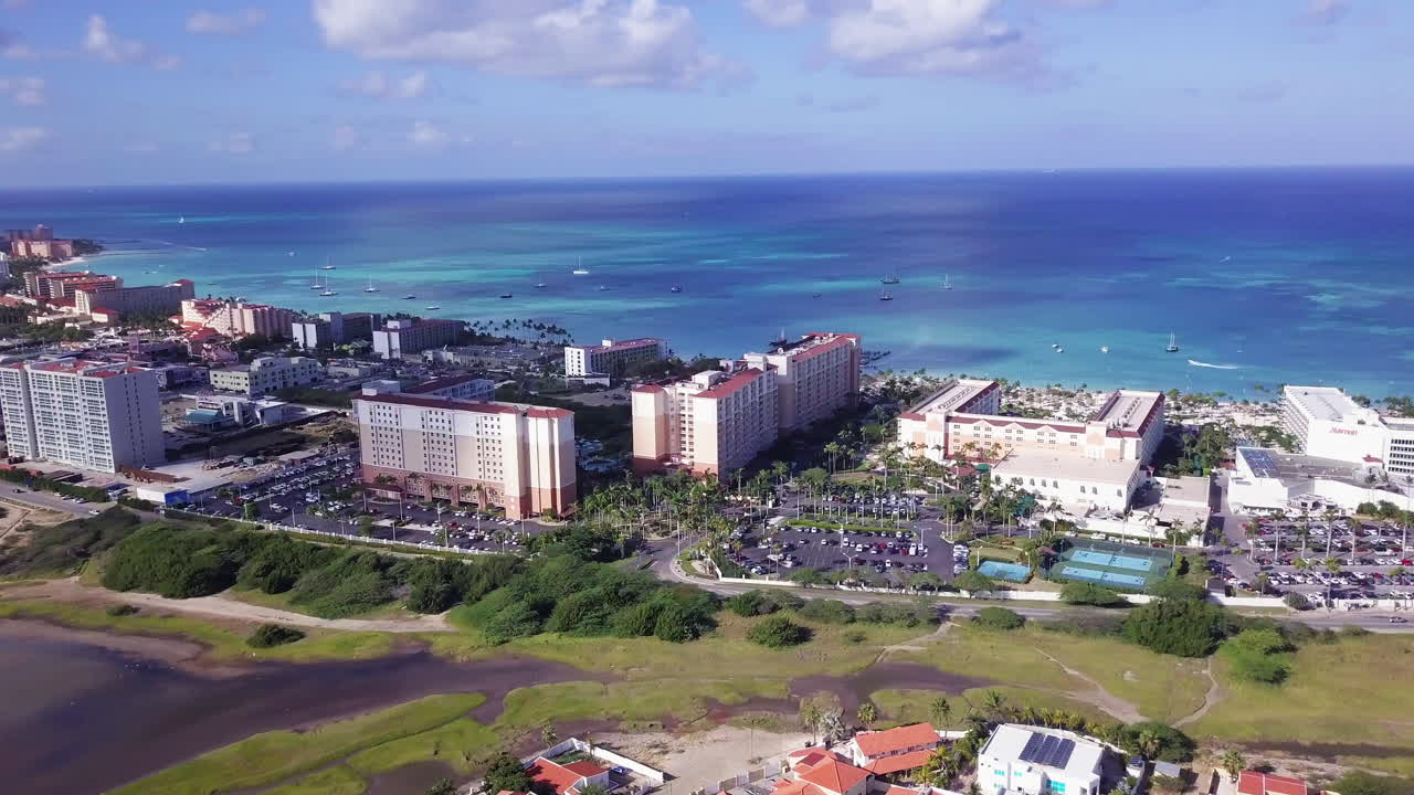 열대의 햇살 가득한 아루바의 아름다운 베이비 블루 바다를 따라 호텔과 주택