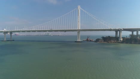 Toma-Aérea-De-Vehículos-Moviéndose-En-El-Puente-De-La-Bahía-De-San-Francisco–oakland-Con-La-Ciudad-Al-Fondo