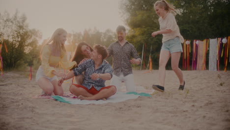 cheerful friends running towards man sitting on sarong