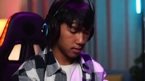 close up of asian teen boy gamer wearing head phones and start play video game on smartphone