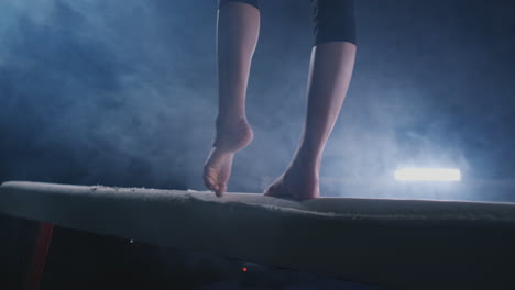 girl gymnast practicing on a balance beam in gym.