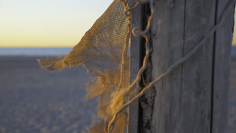 Schöne-Aufnahme-Eines-Alten-Fischernetzes,-Das-An-Einem-Strand-In-Der-Nähe-Von-Wasser-Sonnenuntergang-Zeitlupe-Gestrandet-Ist