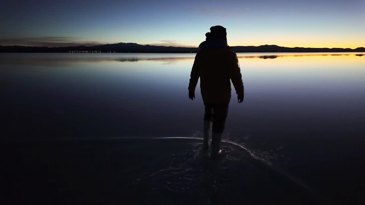 Sagoma di una persona che cammina su una salina al tramonto.