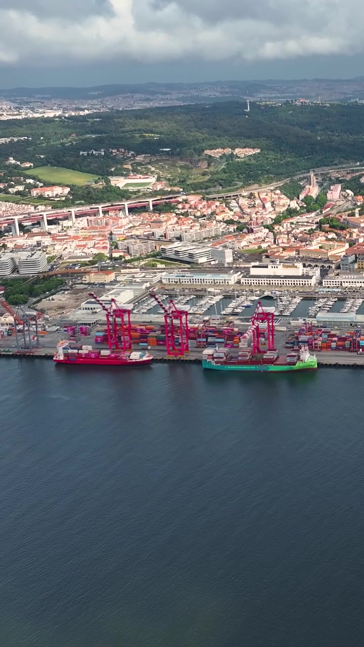 View shows a busy container terminal with various shipping containers stacked. Cargo ships are docked at the port. The terminal plays a key role in international trade and freight transportation.