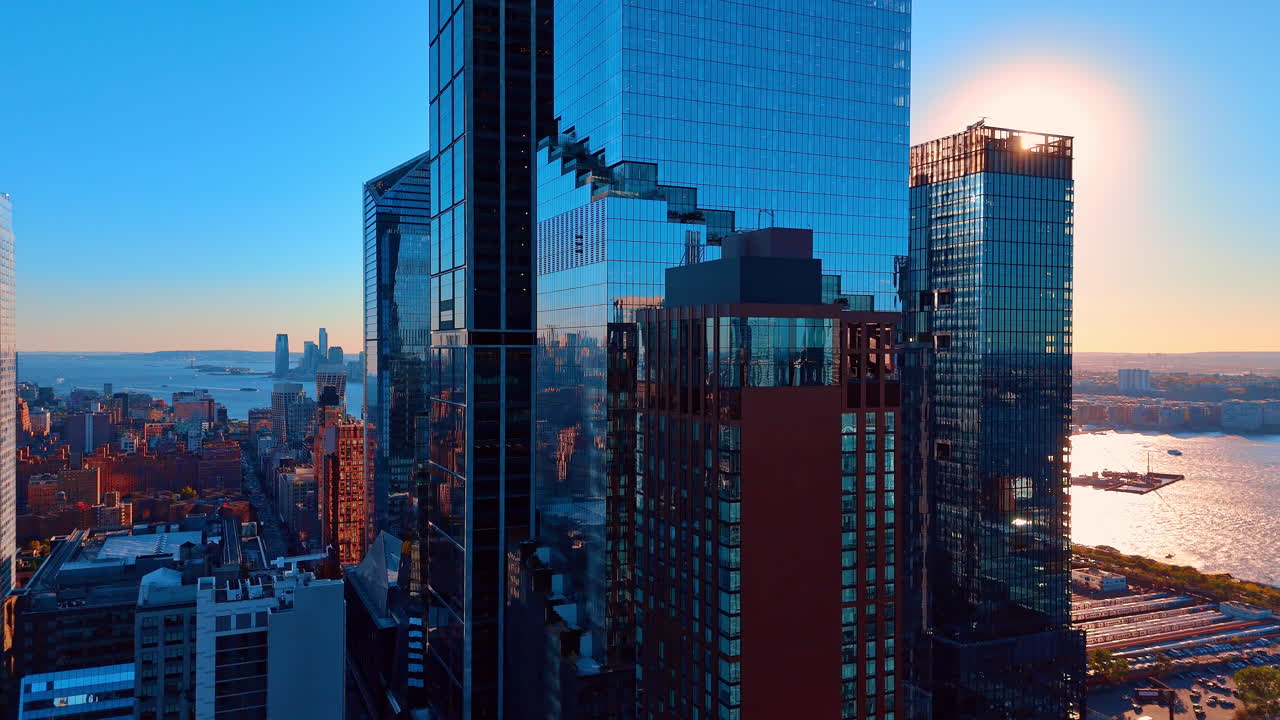 Skyline di moderni grattacieli di vetro al tramonto sul fiume. Vista grandangolare di alti edifici in vetro e del fiume durante un tramonto vibrante con riflessi dorati.
