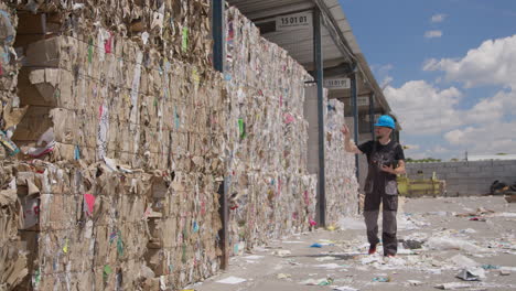 worker counts bales of cardboard and paper at recycling plant, slomo