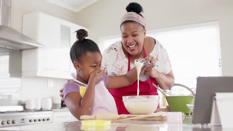 Feliz-Madre-E-Hija-Afroamericanas-Inalteradas-Horneando-En-La-Cocina-Usando-Una-Tableta,-En-Cámara-Lenta