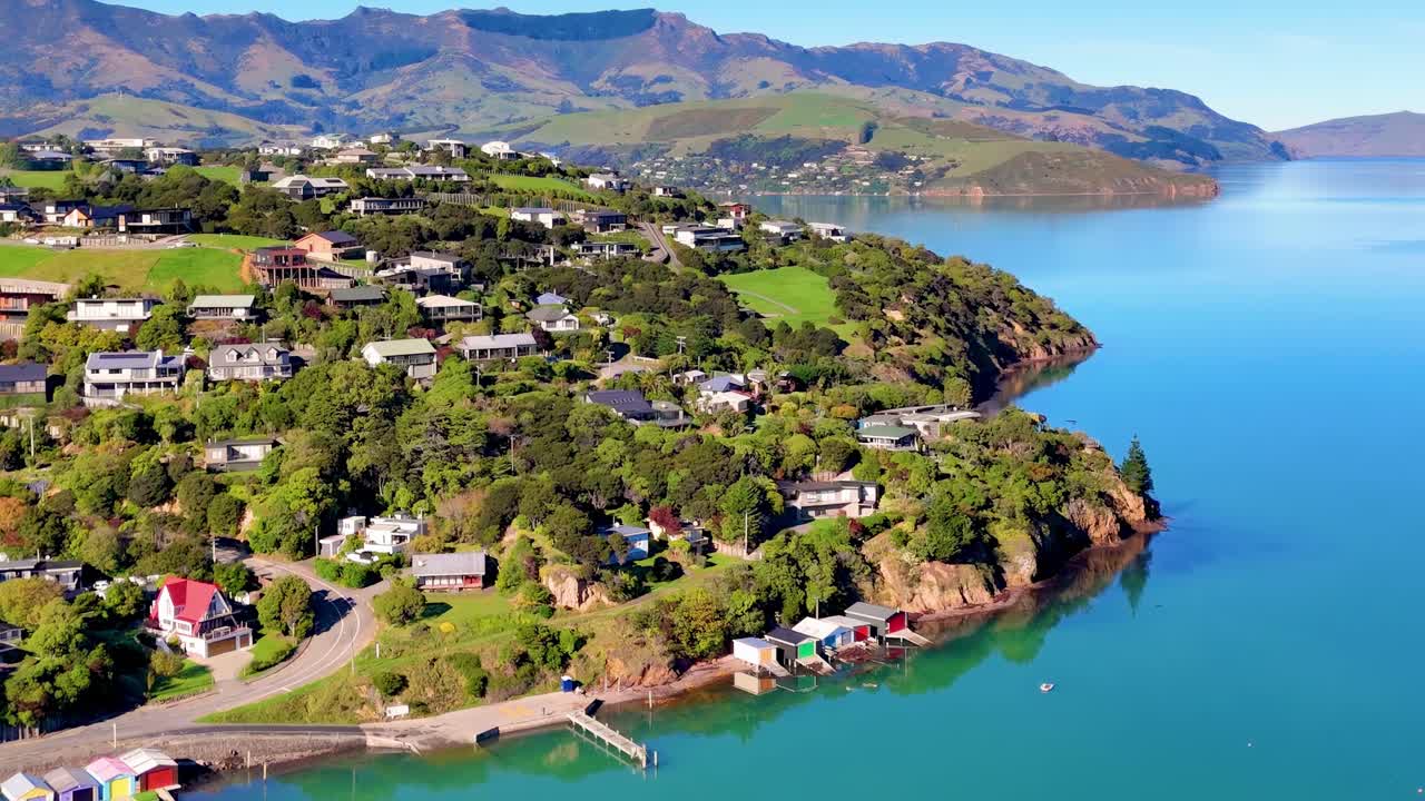Cropped aerial footage showcasing coastal homes, lush greenery, and expansive blue waters under clear skies.