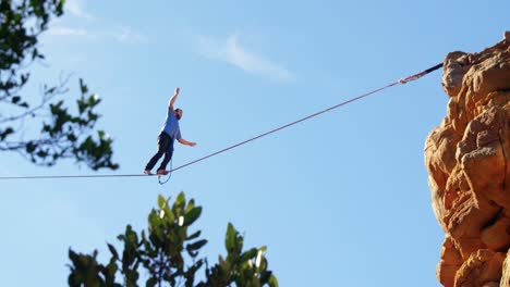 atleta de línea alta equilibrando en slackline en la montaña rocosa 4k