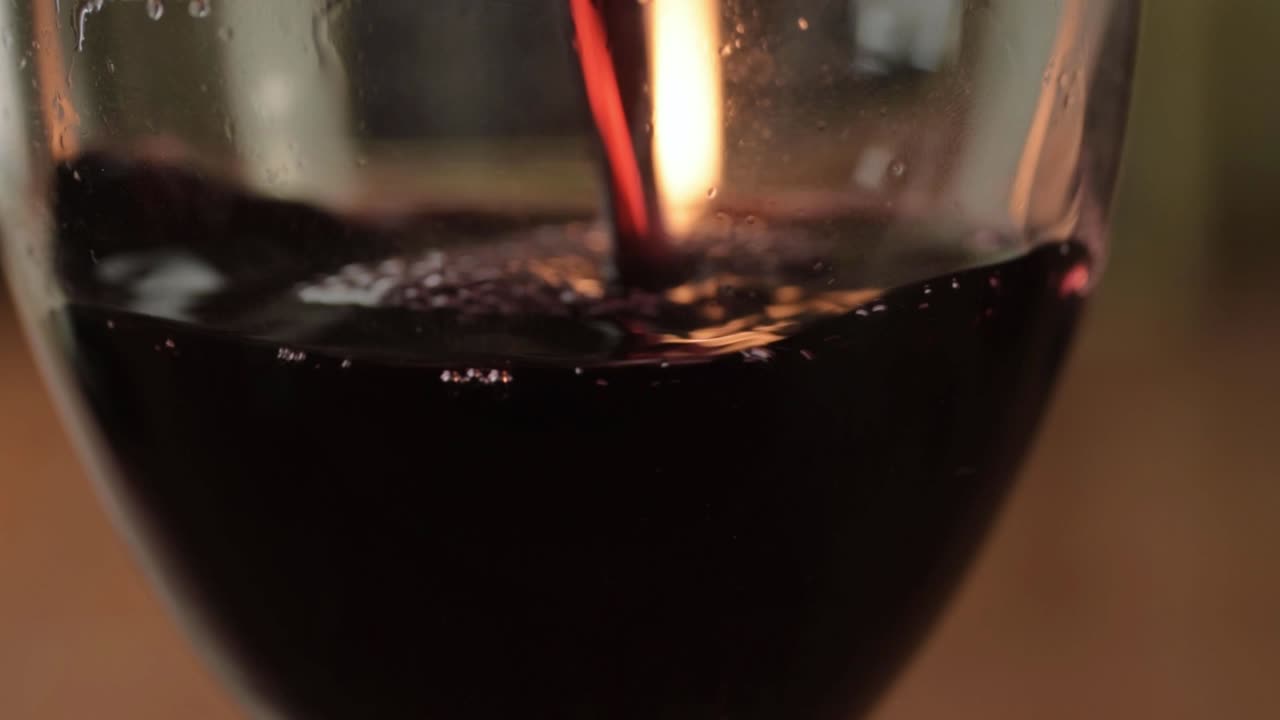 verter vino tinto en un vaso con fondo de vela caliente de cerca