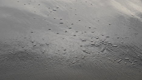 Burbujas-Desapareciendo-Lentamente-De-La-Arena-Que-Fueron-Producidas-Por-Las-Olas-Golpeando-La-Playa