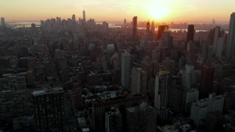 Backwards-fly-above-city.-Aerial-view-of-cityscape-against-golden-sunset.-Manhattan,-New-York-City,-USA