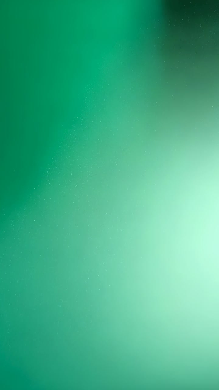 Video verticale: Gradiente verde sfocato che si sposta mostrando un punto più scuro in primo piano, da uno spostamento di messa a fuoco