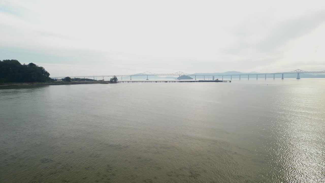 Drone orbit right to reveal Richmond Bridge from Point Molate Beach Richmond California USA, backlit