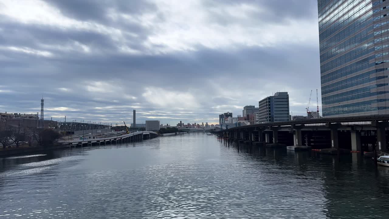 A calm urban river view with bridges and modern buildings in Tokyo on a cloudy day