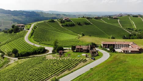 el dron vuela desde arriba y llega a una granja en ruinas cerca de una carretera en la cima de las colinas de langhe.
