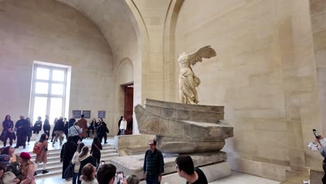 people around winged victory at the louvre. nike, victory of samothrace with public