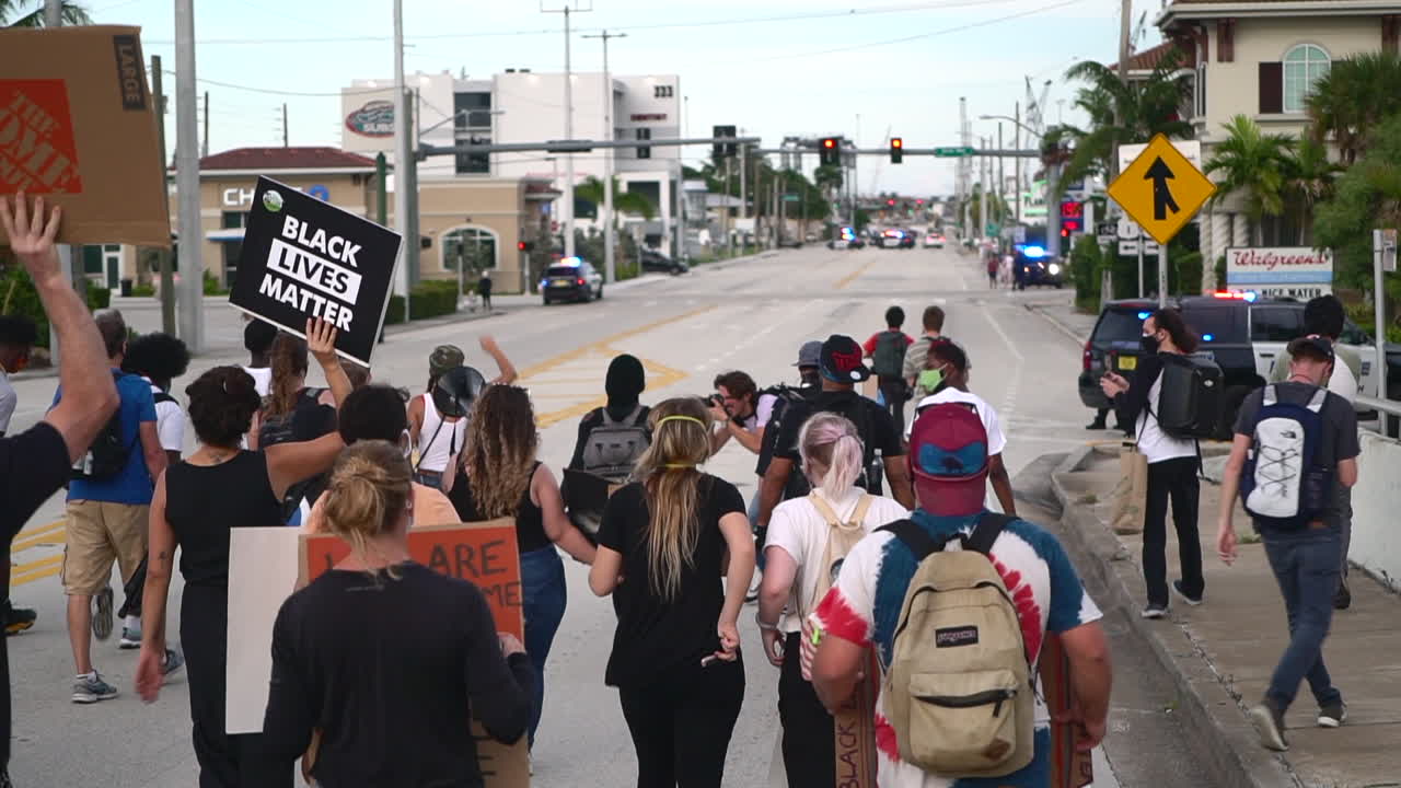 Crowd of mixed ethnicity protestors marching towards police roadblock