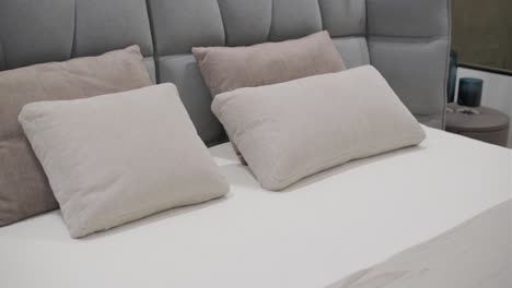 un dormitorio moderno muestra una gran cama tapizada con una cabecera de tuft en tonos grises, completa con ropa de cama y almohadas coordinadas