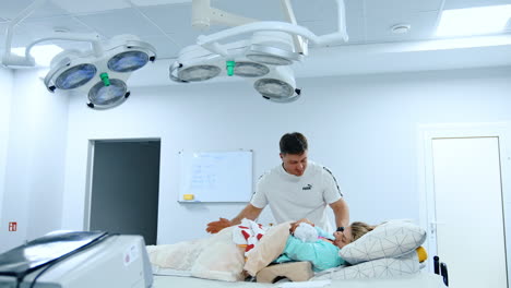 caucasian mom lies in hospital bed holding her baby. mother breastfeeding newborn and father kisses his wife and child.