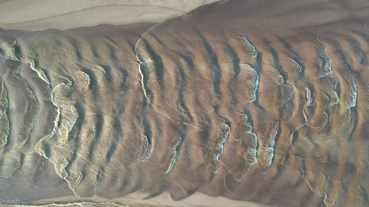 Aerial View of Rippled Sand and Water