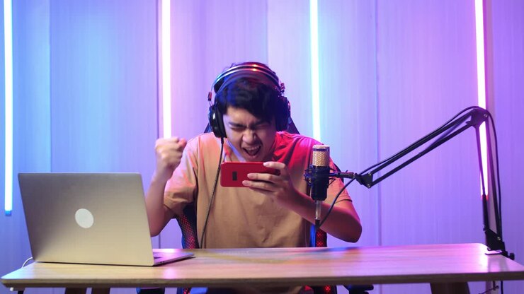Uomo asiatico che gioca a un videogioco con il telefono cellulare, poi festeggia durante una diretta streaming.