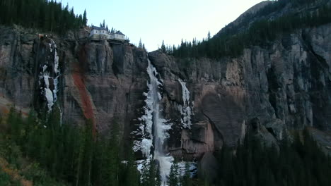 Bridal-Veil-Falls-Telluride-Colorado-Luftdrohne-Gefrorenes-Eis-Wasserfall-Herbstsonnenuntergang-Kühle-Schattige-Felsige-Berge-Silverton-Ouray-Millon-Dollar-Highway-Historische-Stadtlandschaft-Langsame-Aufwärtsbewegung-Des-Auslegers