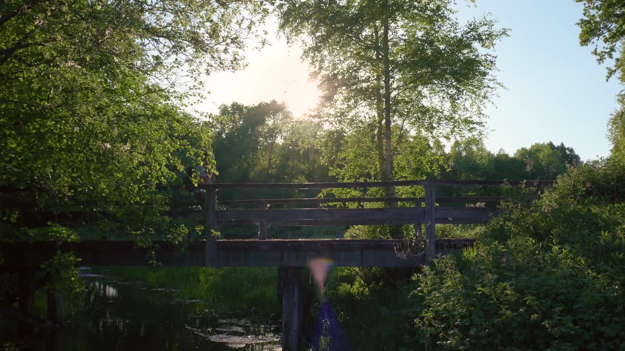 Man Walking Across Wooden Bridge in Forest
