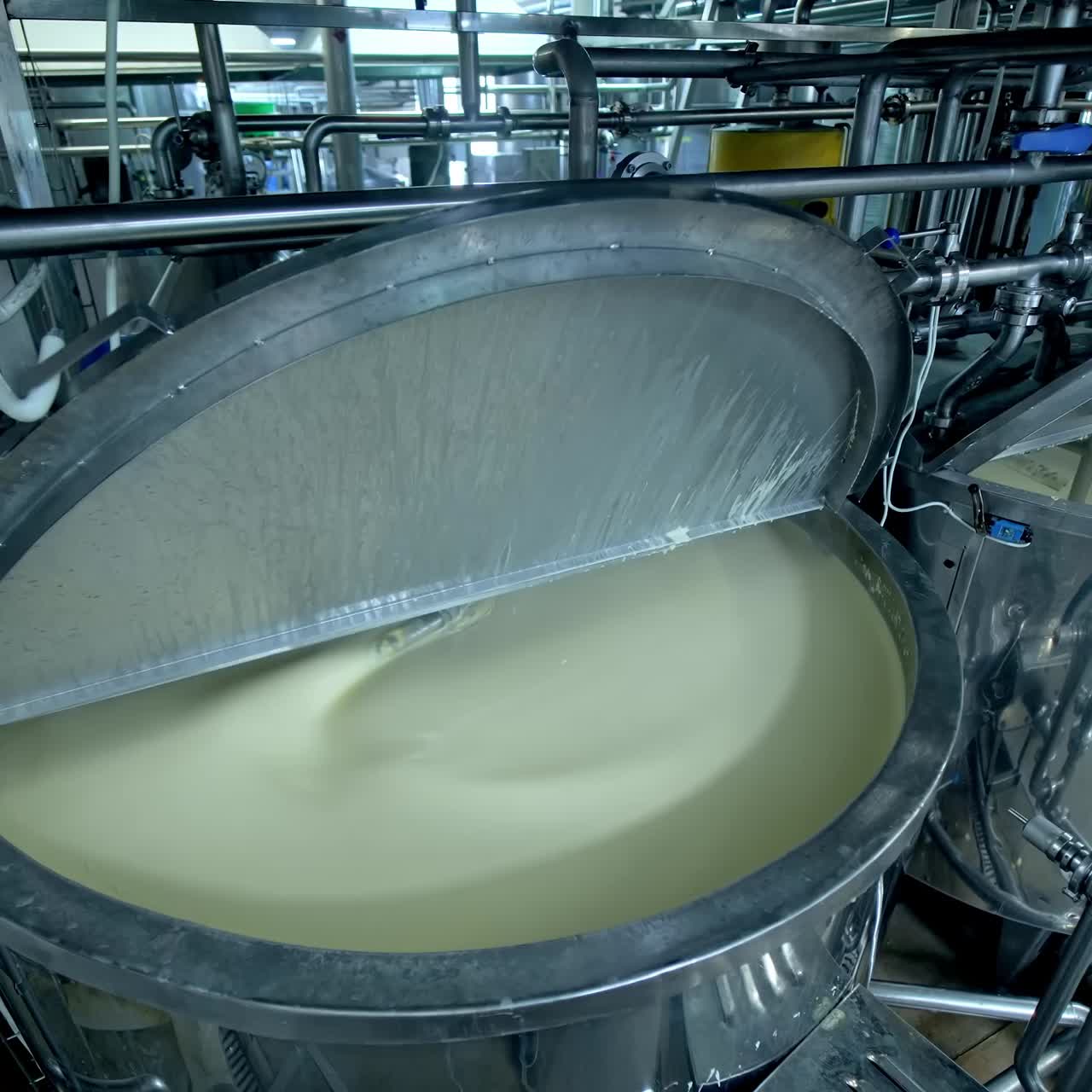Two big steel tanks full of cream with automatic mixing. Metal reservoirs with open lids at the modern milk factory. Close up