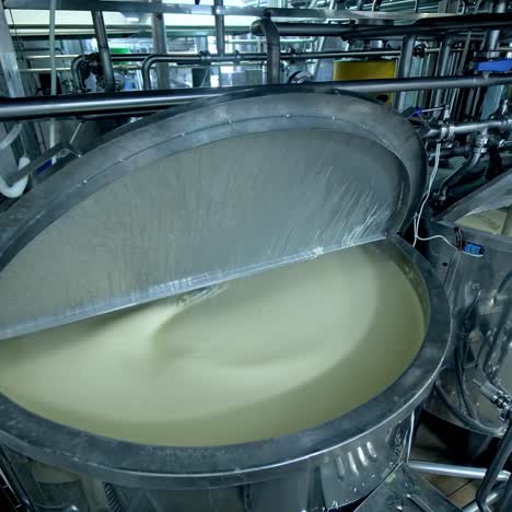 two big steel tanks full of cream with automatic mixing. metal reservoirs with open lids at the modern milk factory. close up